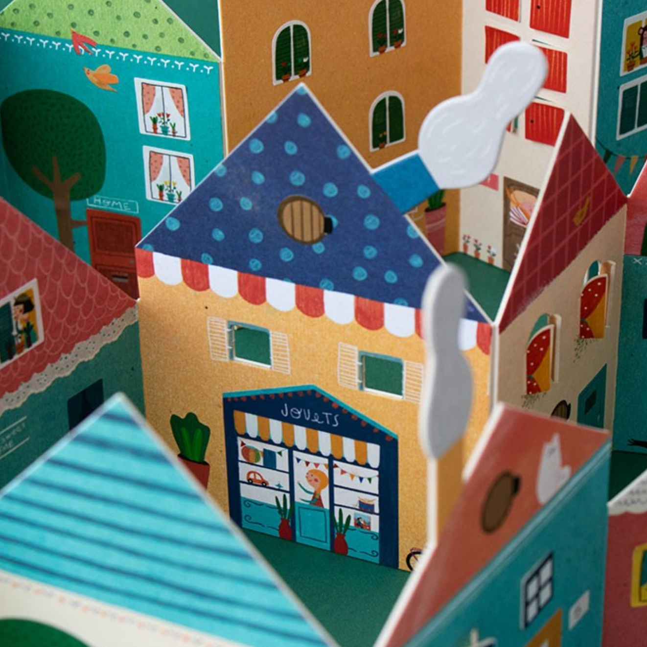Colorful paper town model with various buildings and a street scene.