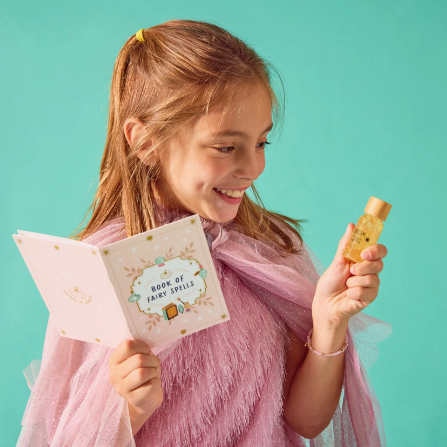 Girl holding a card and a small bottle against a teal background