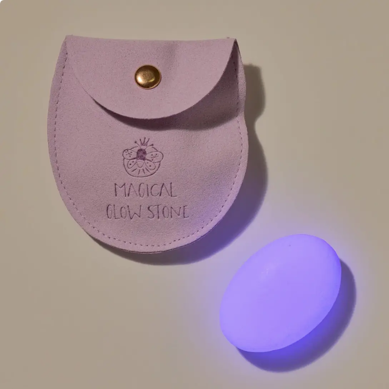 Purple pouch labeled 'Magical Glow Stone' with a glowing purple stone on a beige background