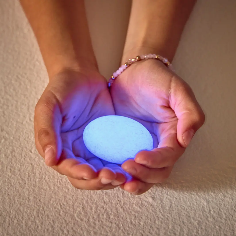Hands holding a glowing blue ball against a neutral background