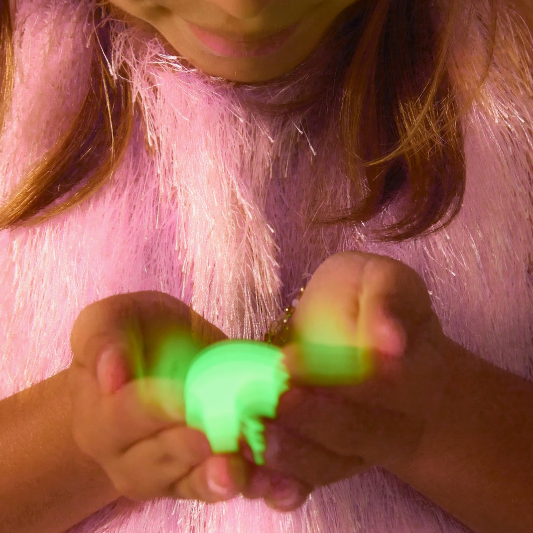 Person holding a glowing green object with a pink background