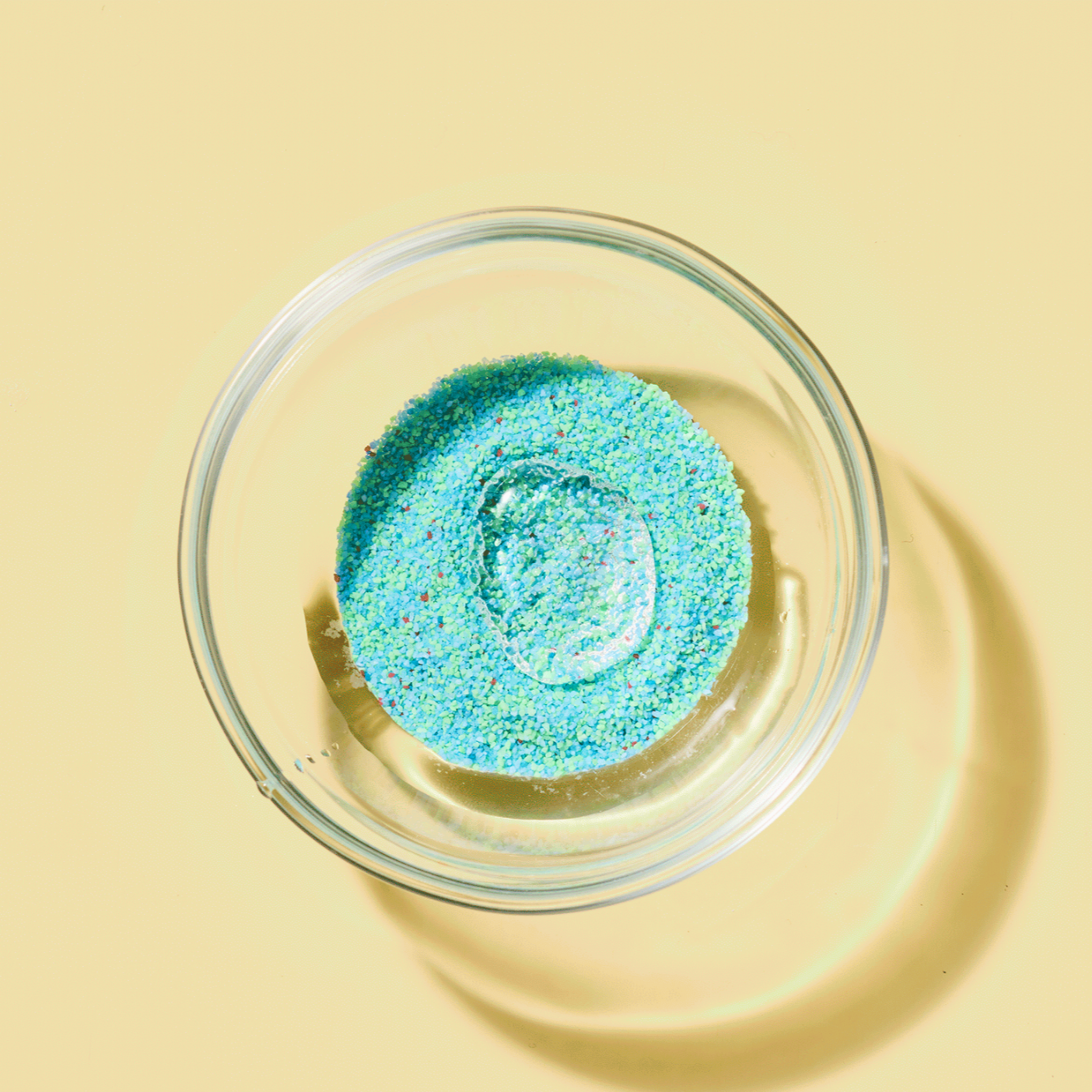 Glass bowl with blue glitter on a yellow background