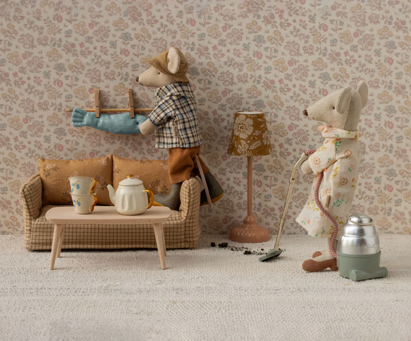 Stuffed animal figures in a living room setting with a sofa, lamp, and coffee table.