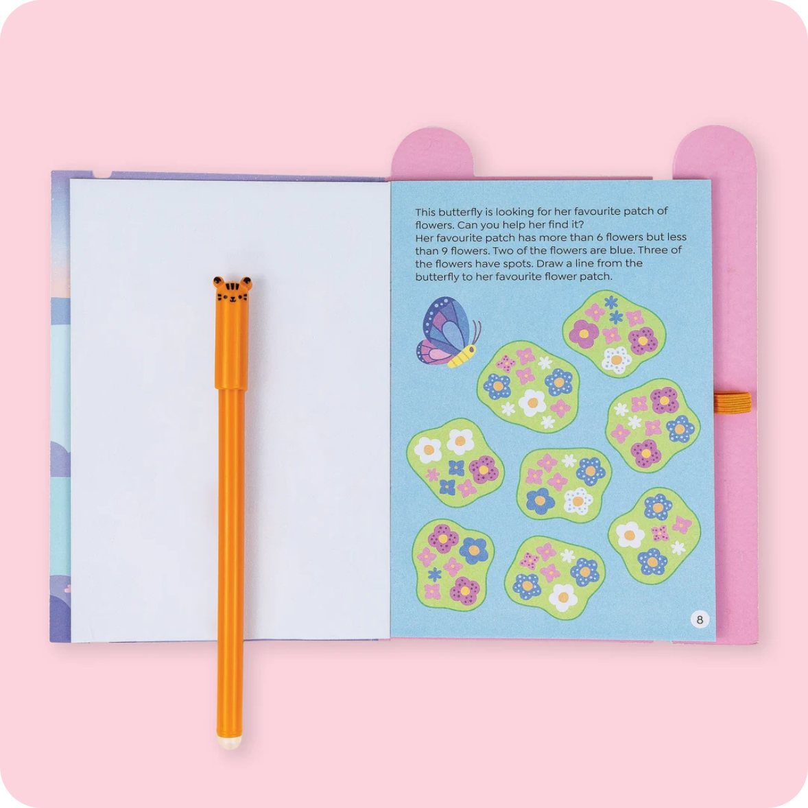 A children's activity book or journal shown open on a pink background, with a matching orange pen placed beside it. The right page has a butterfly illustration and flower-spot drawing exercises.