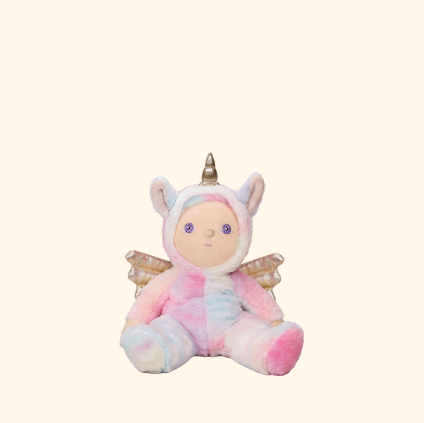 A plush unicorn doll with pastel pink, blue, and white tie-dye fur, featuring a gold horn, white ears, and small gold wings, set against a solid cream background.