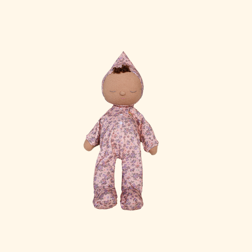 A small fabric doll with a brown cloth face and arms, wearing a pink floral hooded jumpsuit, centered on a plain warm cream background.