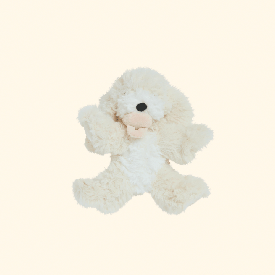A fluffy cream-colored plush dog toy with a soft beige snout and black nose, centered on a solid pale cream background.