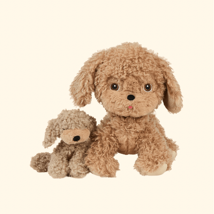 Two curly plush dog toys in shades of light brown and tan, posed together on a plain warm cream background.