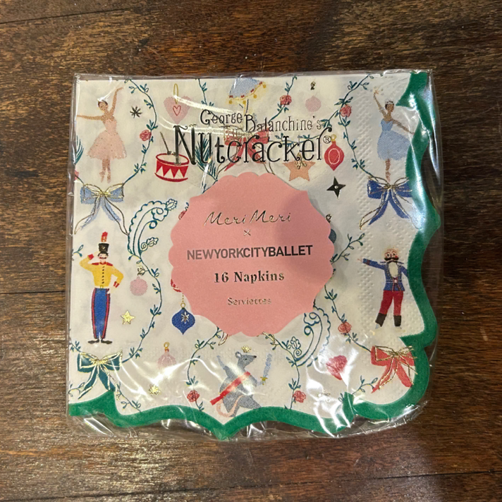 A packaged set of 16 napkins featuring a New York Ballet theme, wrapped in clear plastic on a dark wooden tabletop. The napkin design has a cream background with green scalloped borders and various ballet dancers and characters in colorful costumes.