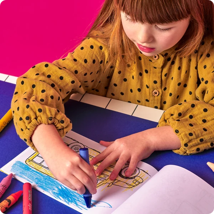 Child coloring in a book with crayons on a pink and purple background