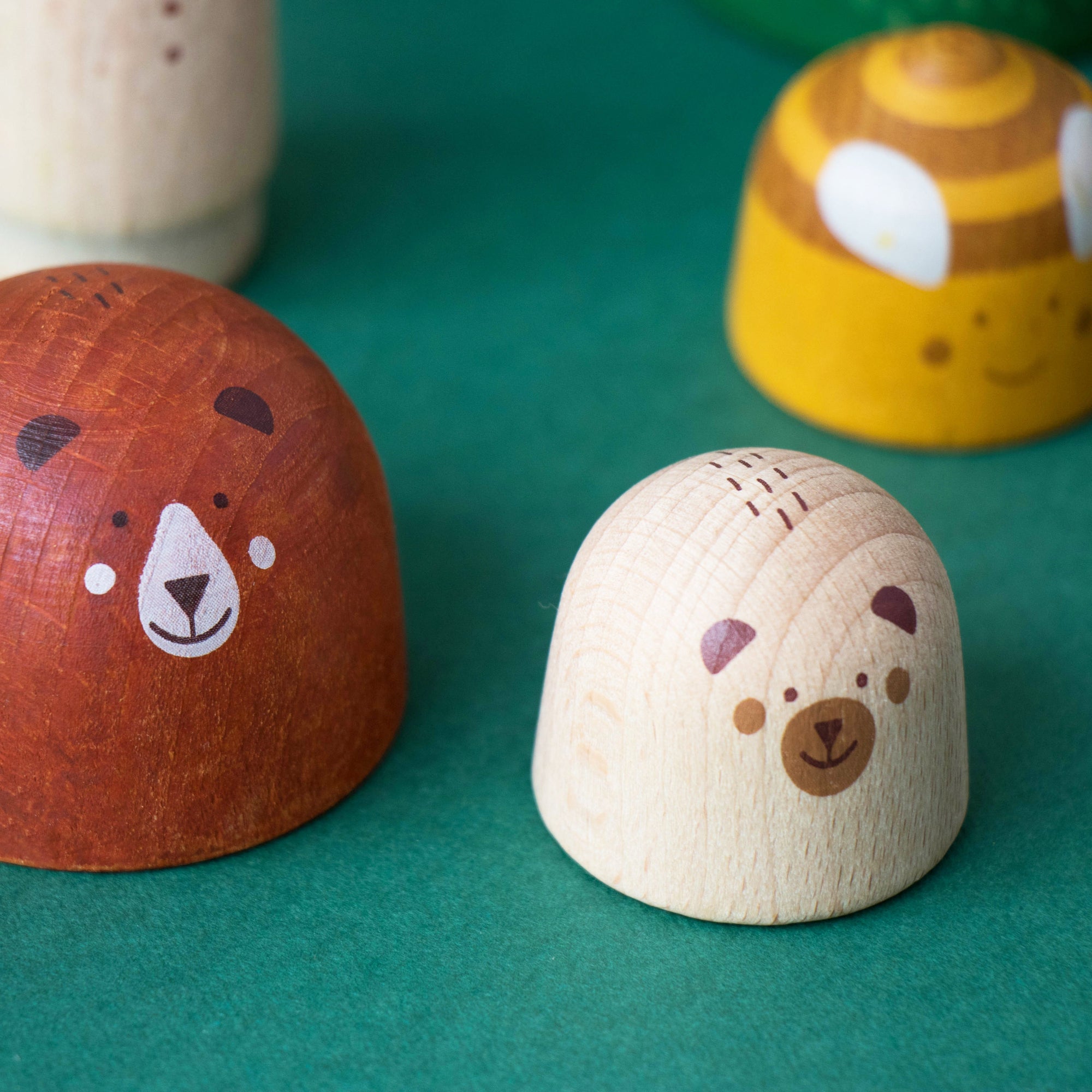 Two wooden bear-shaped objects on a green surface with additional bear-shaped items in the background.