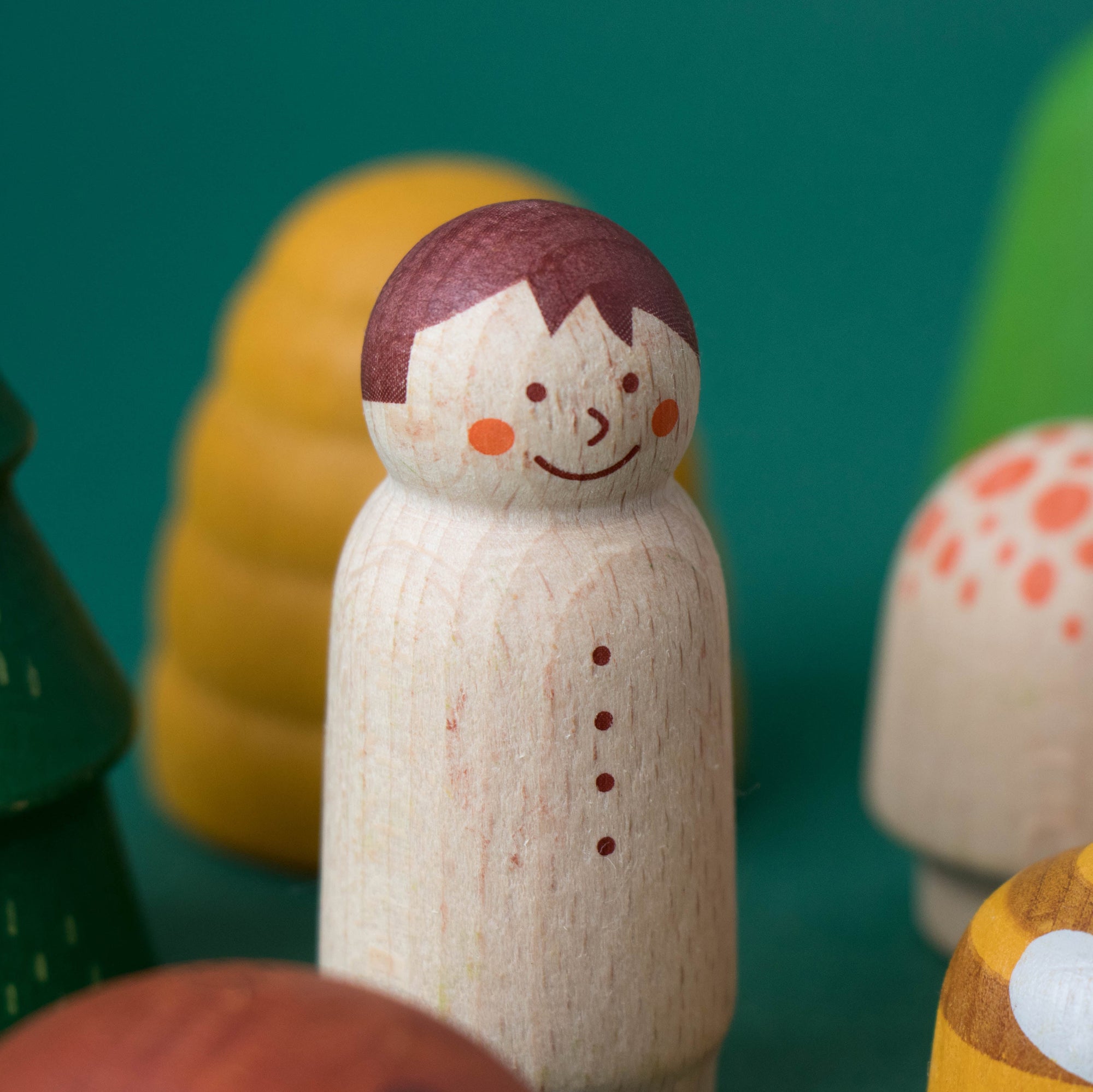 Wooden peg figure with colorful mushroom-like figures on a teal background