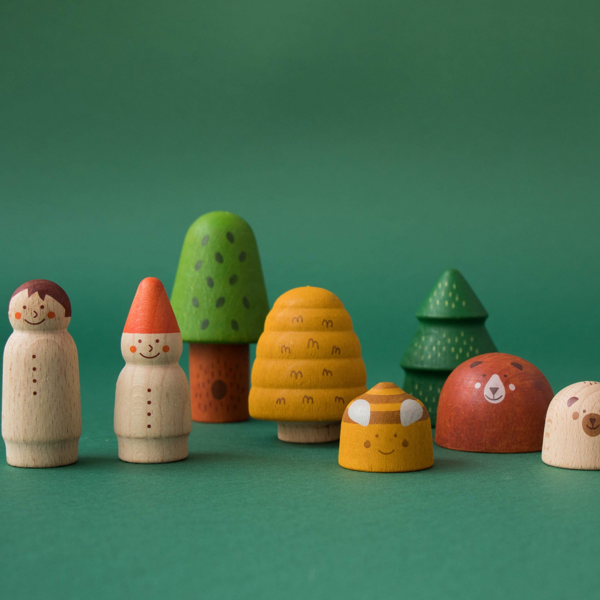 Set of colorful wooden toy figures on a green background