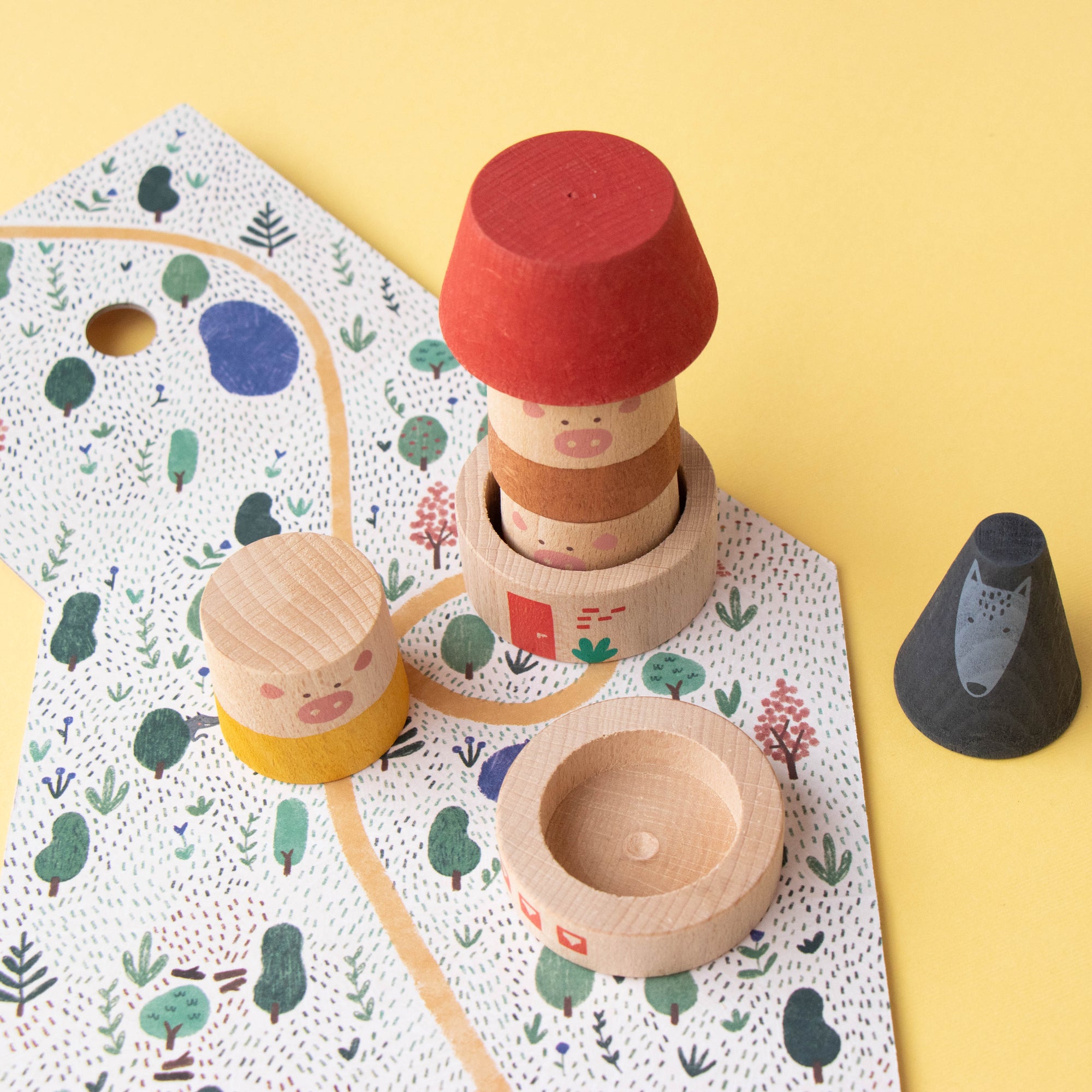 Set of wooden toys including stackable rings and a cone on a patterned mat with a yellow background