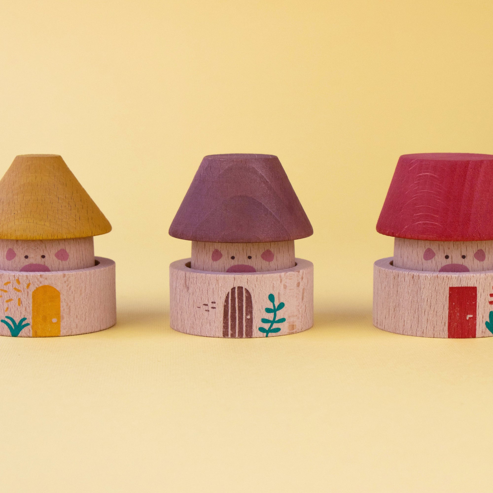 Three colorful toy houses with different roof colors on a yellow background