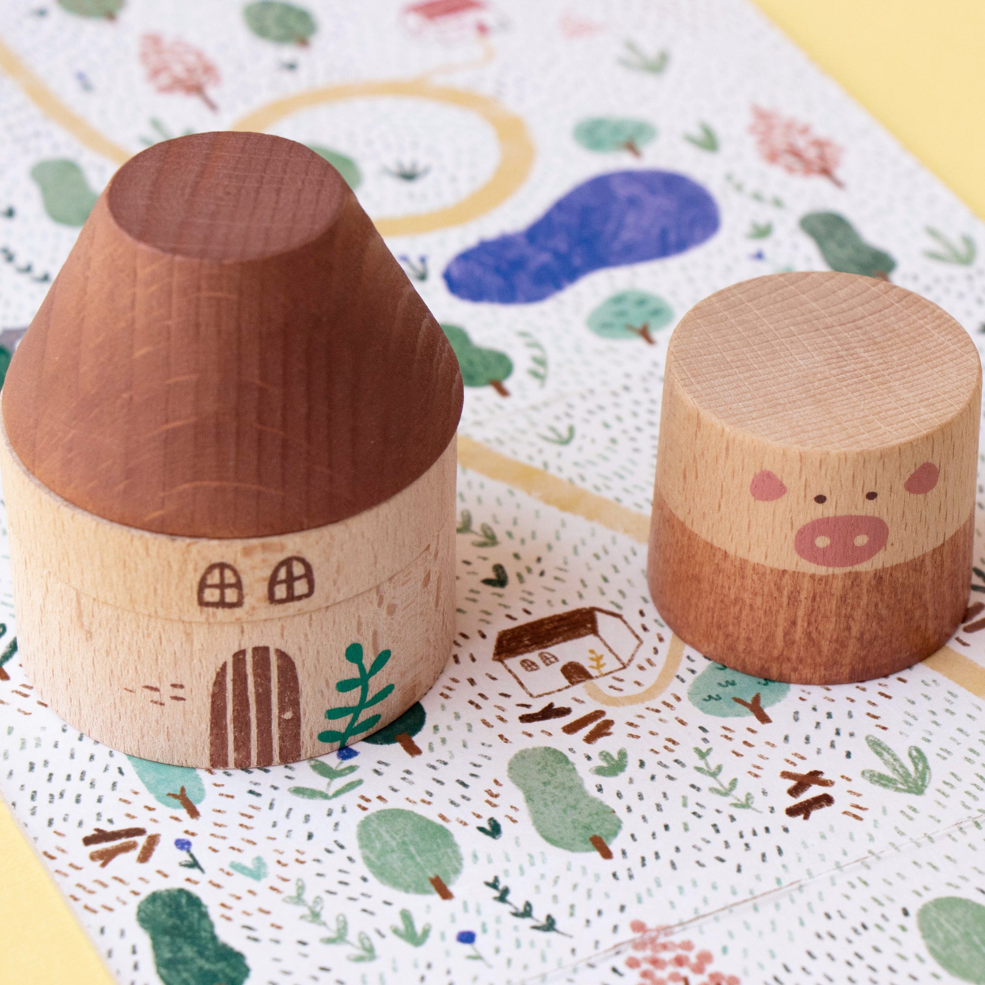 Two wooden toys shaped like houses on a decorative mat with colorful patterns.