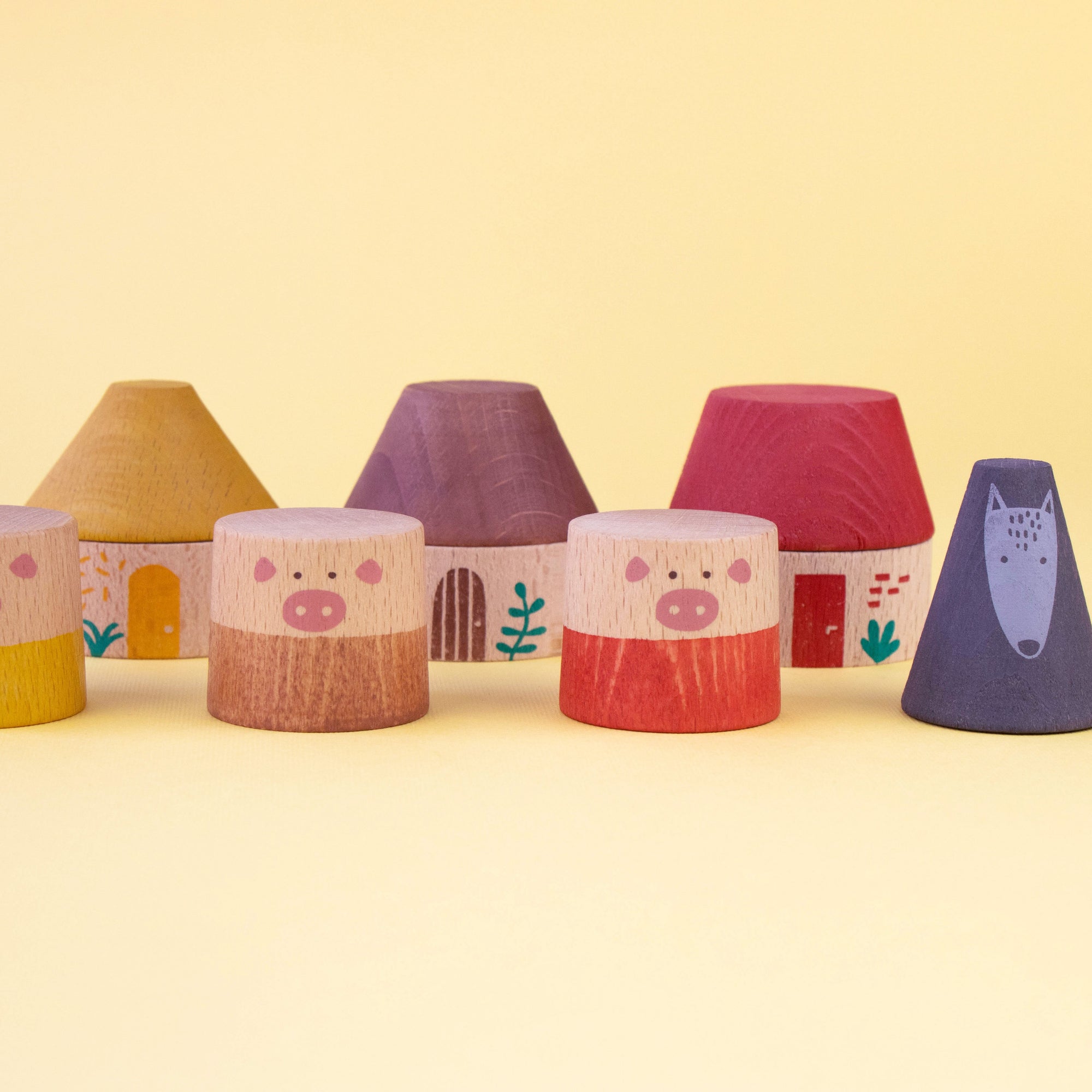 Set of colorful toy houses with pig designs on a yellow background