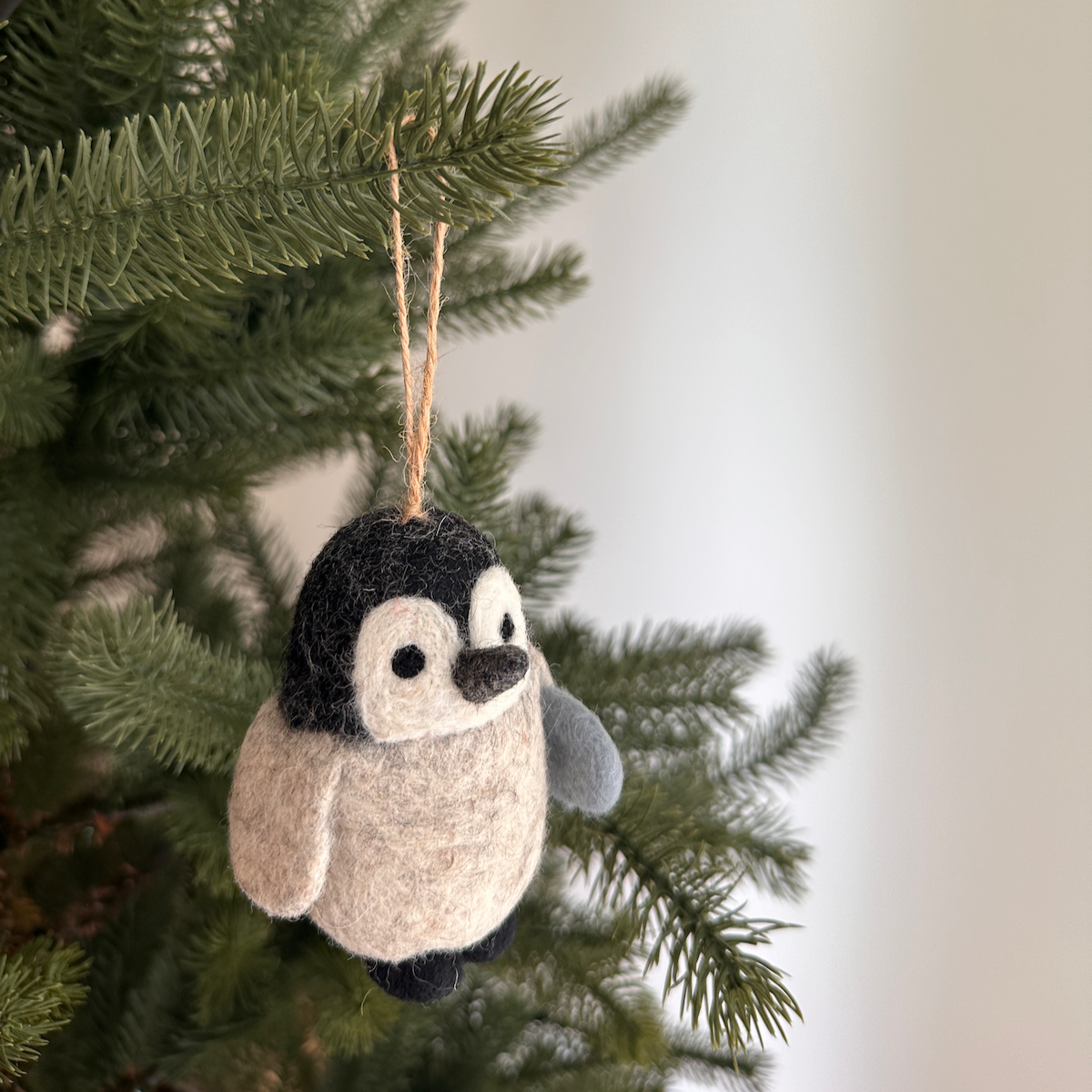 Felt penguin ornament hanging on a Christmas tree