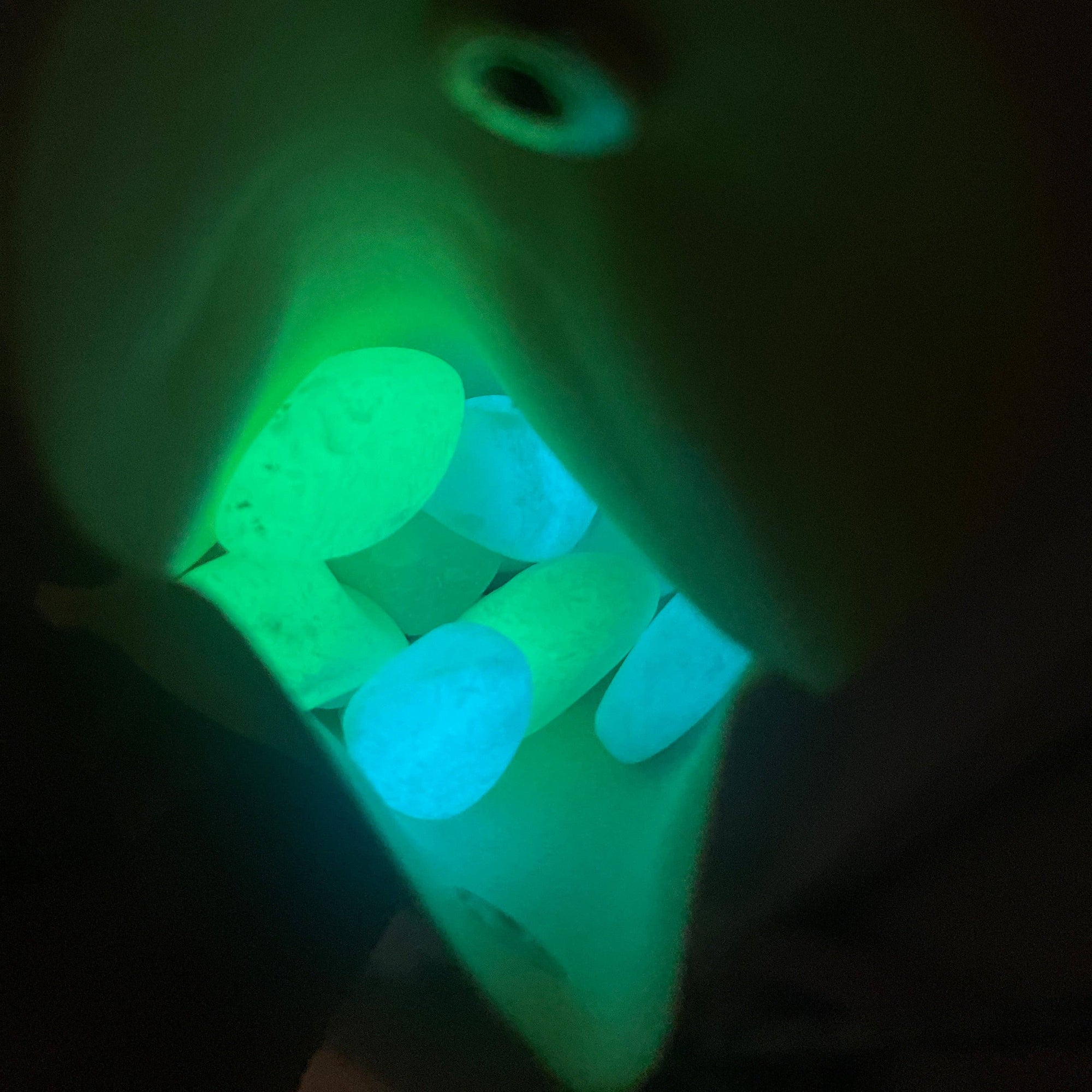 Glowing green toothbrush head in a dark setting