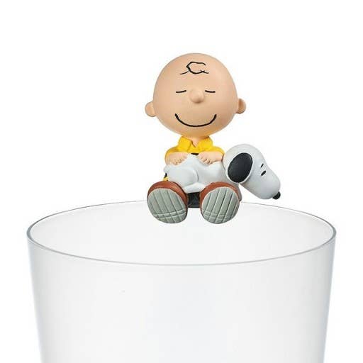 Figurine of a character sitting on a transparent cup with a white background