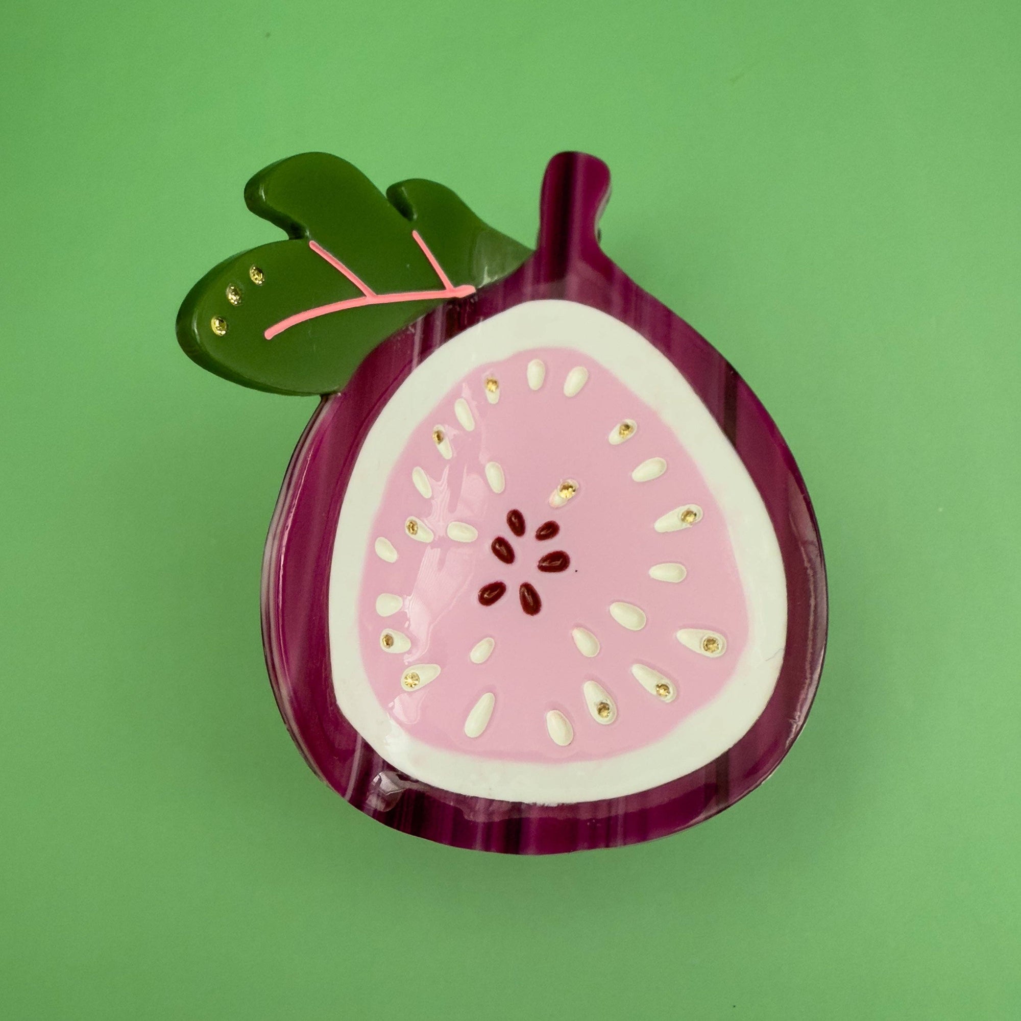 Decorative item shaped like a sliced fig on a green background