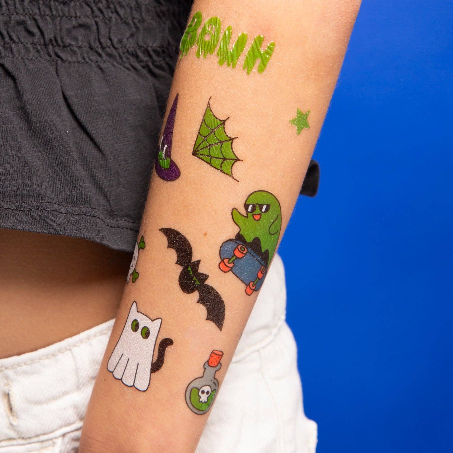 Halloween-themed temporary tattoos on a person's arm with a blue background