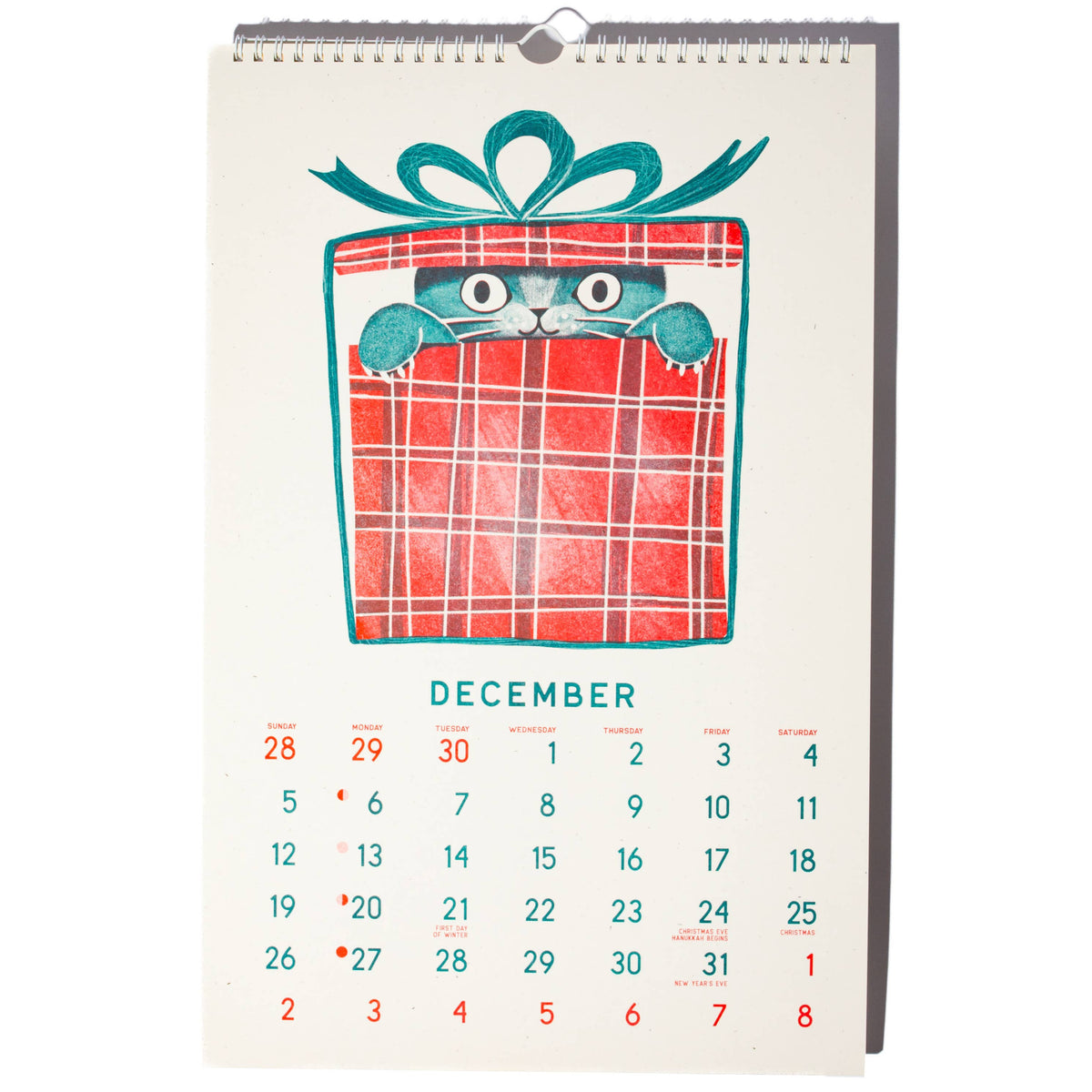 A hanging desk calendar page featuring a red gift box illustration with a teal bow and the word December at the top, with a grid of dates below, shown on a plain white background.