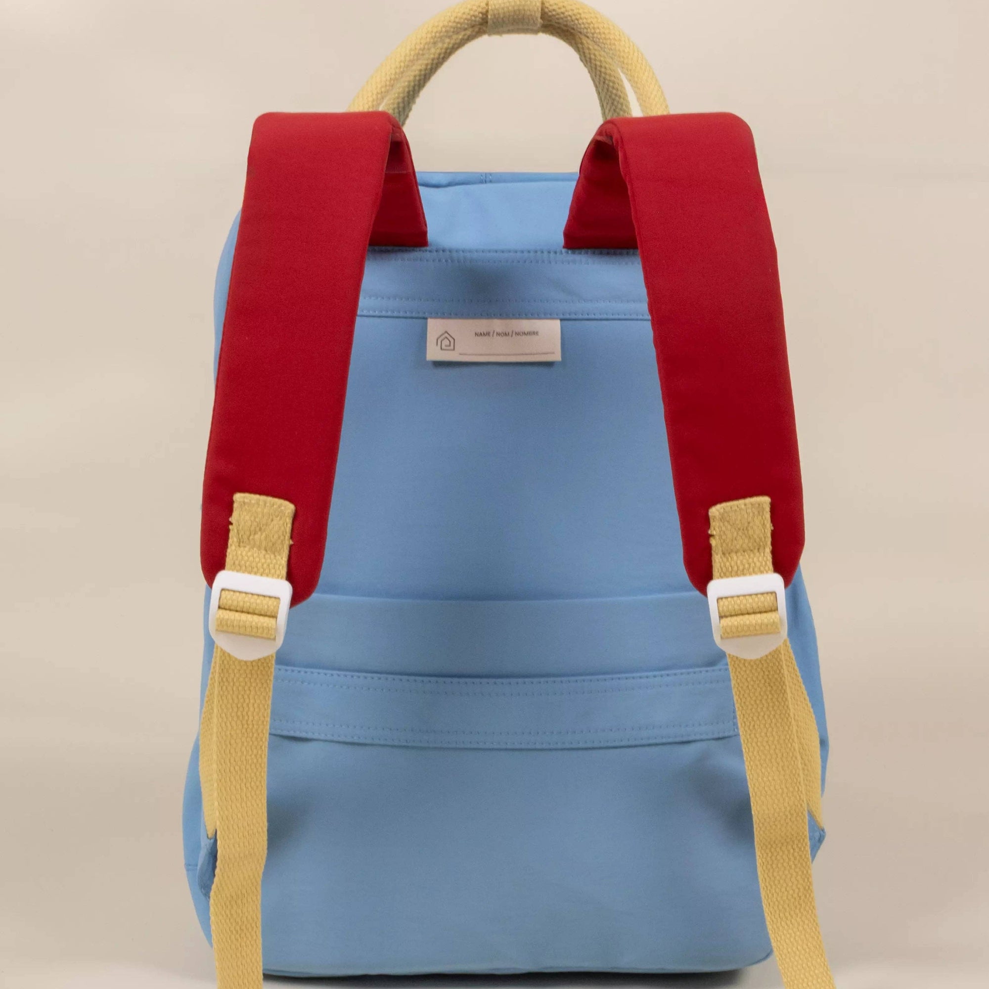 Blue backpack with red straps and yellow accents on a beige background