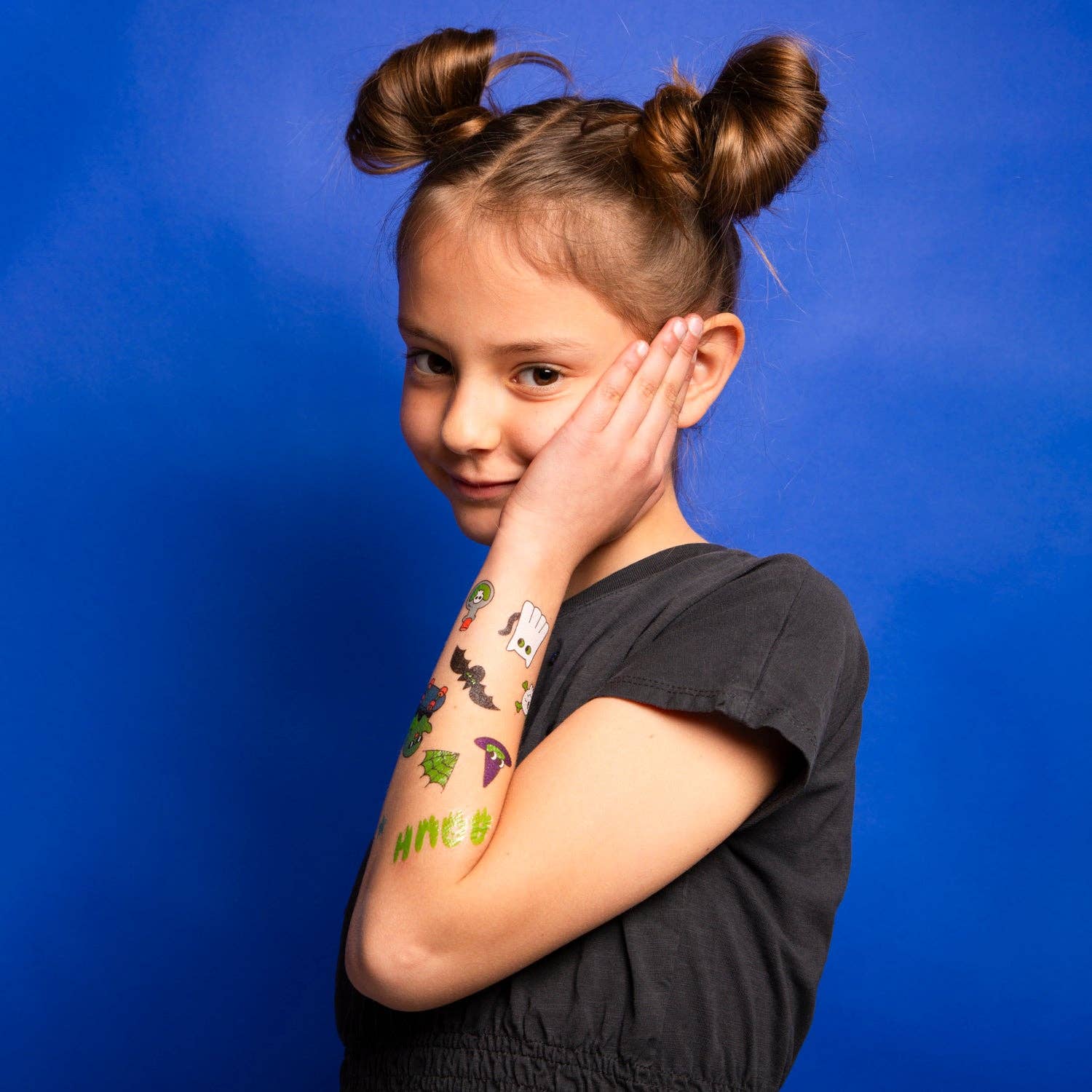 Young girl with colorful temporary tattoos on her arm against a blue background