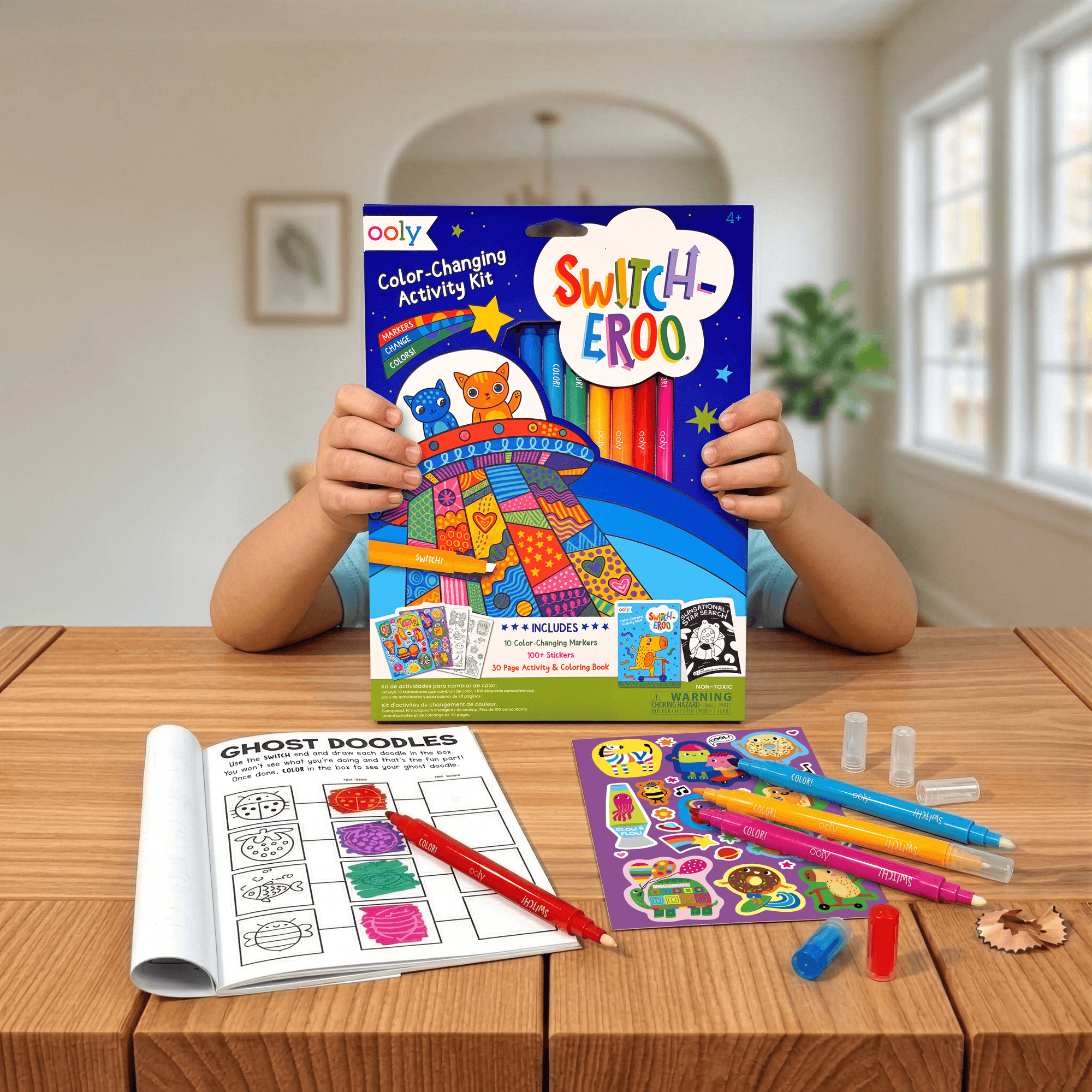 Child holding a 'Switch-Eeroo' color changing activity kit with coloring book and markers on a table.