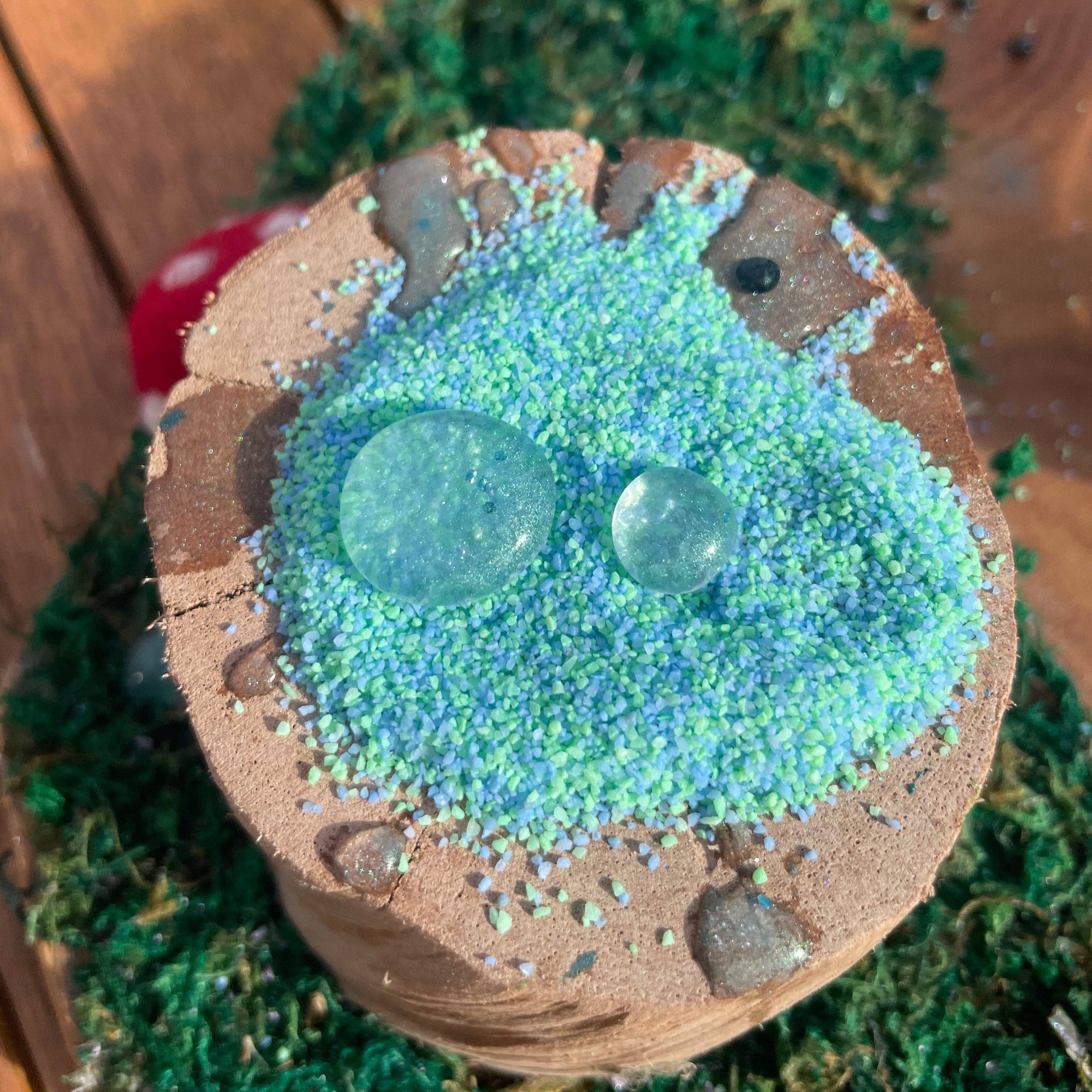 Decorative stone with green beads and stones on a wooden surface