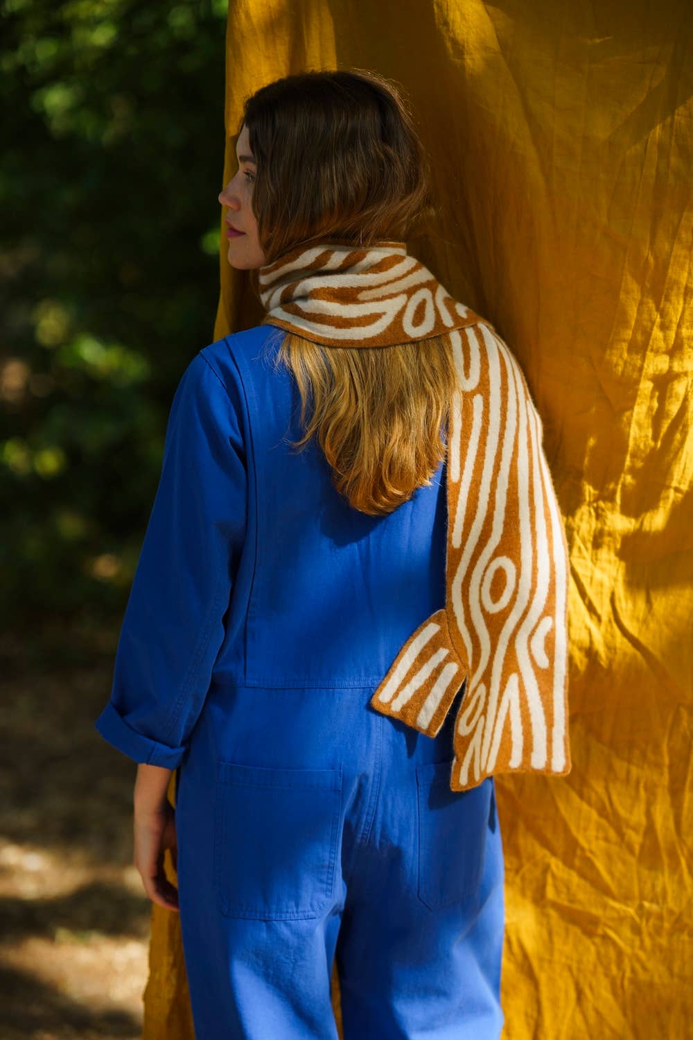 Person wearing a blue outfit with a zebra-patterned scarf against a yellow fabric background