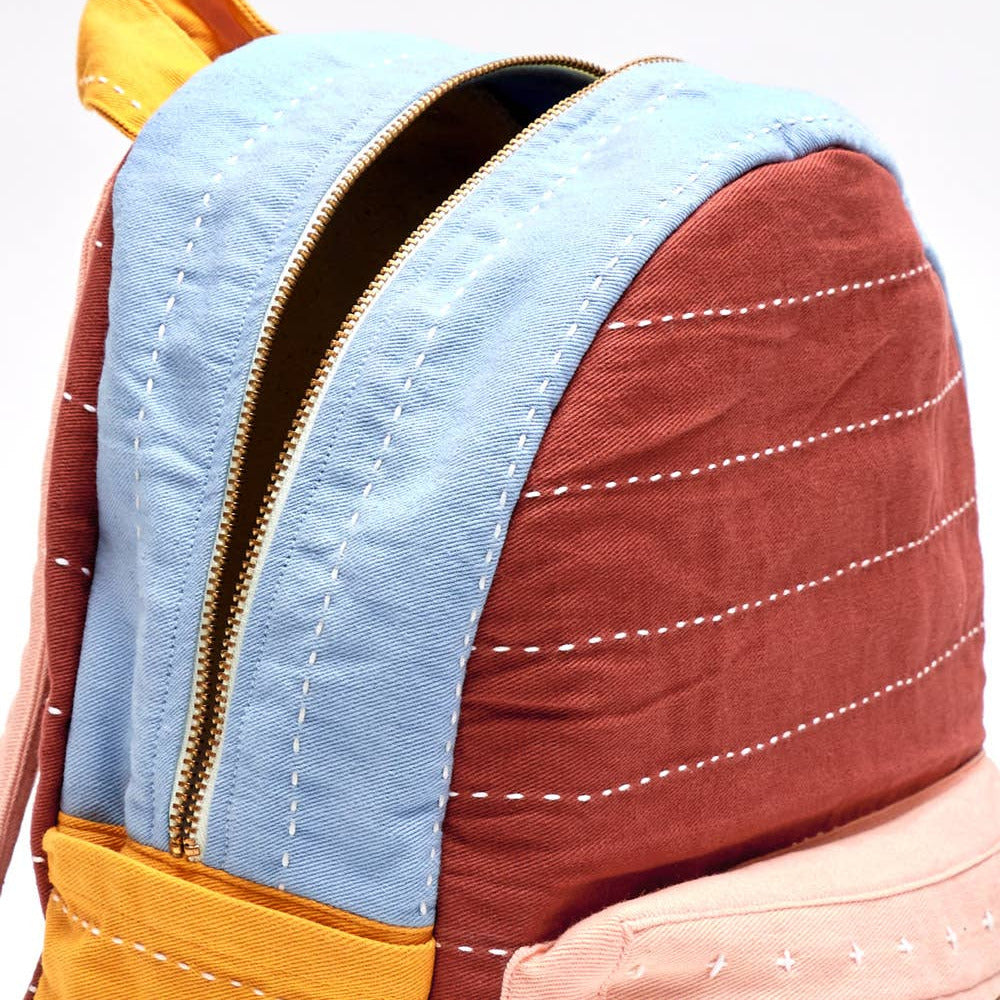 Multicolored backpack with blue, yellow, and brown sections on a white background