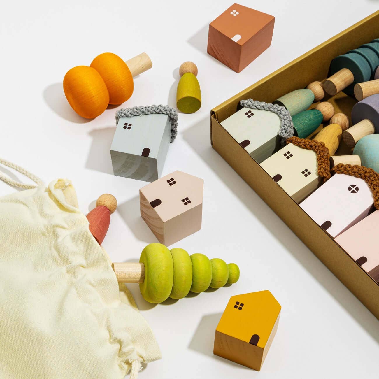 Colorful wooden toys including houses and a bag on a white background