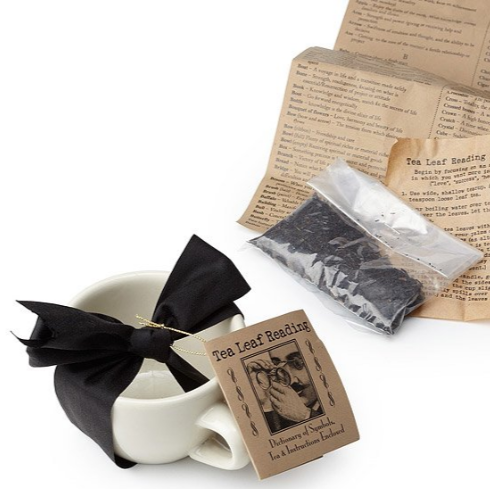 Tea leaf reading kit with a cup, black ribbon, and instructions on a white background