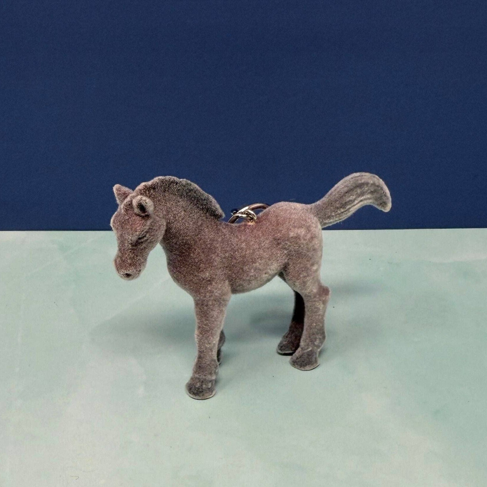 Plush toy horse on a light surface with a dark blue background