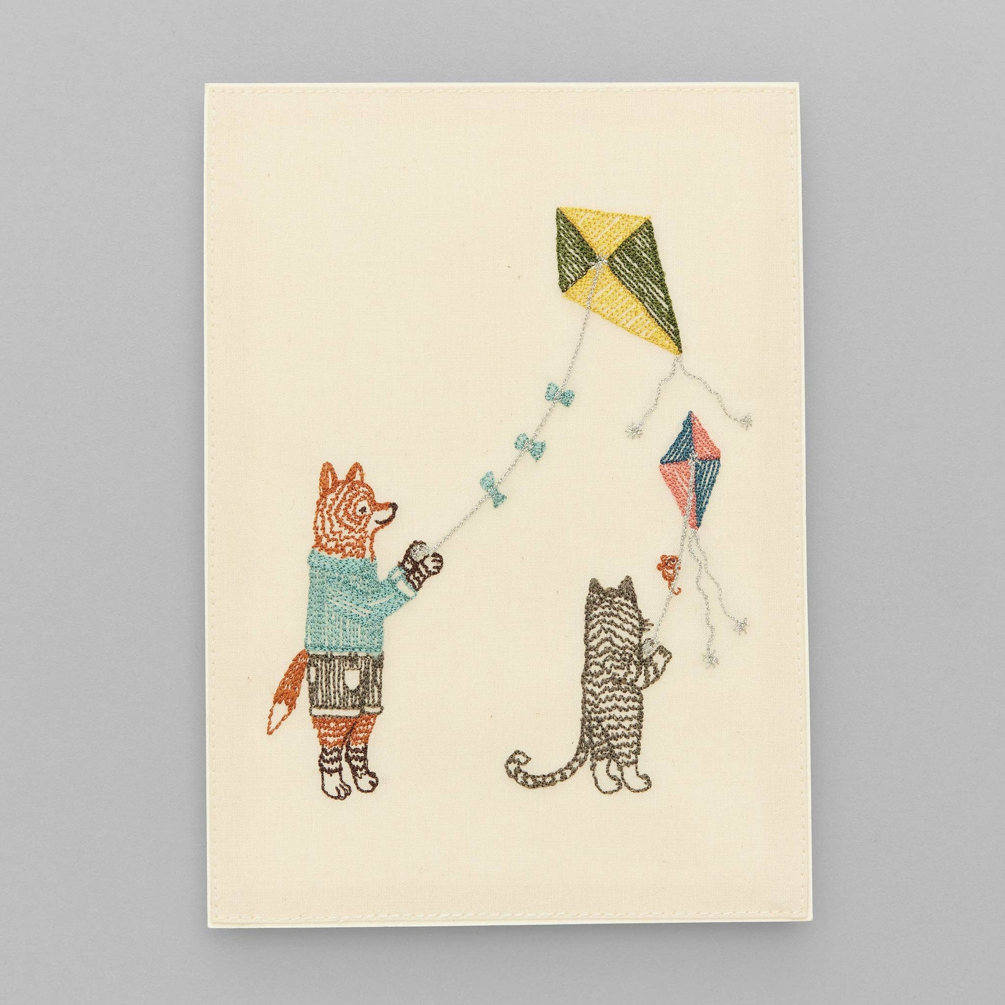 Illustration of a fox and a cat flying kites on a beige background