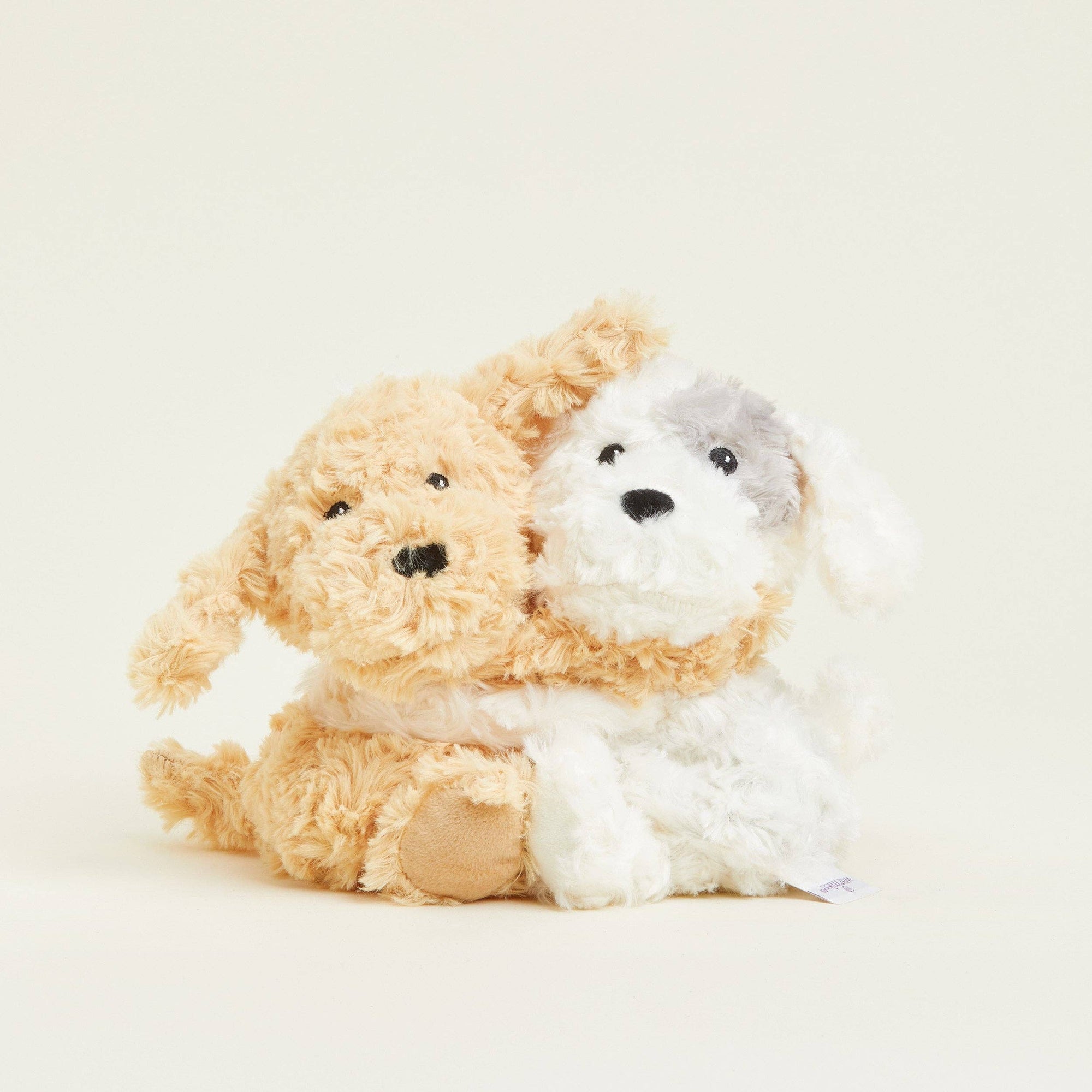 Two plush toys, one brown and one white, sitting together on a light background.