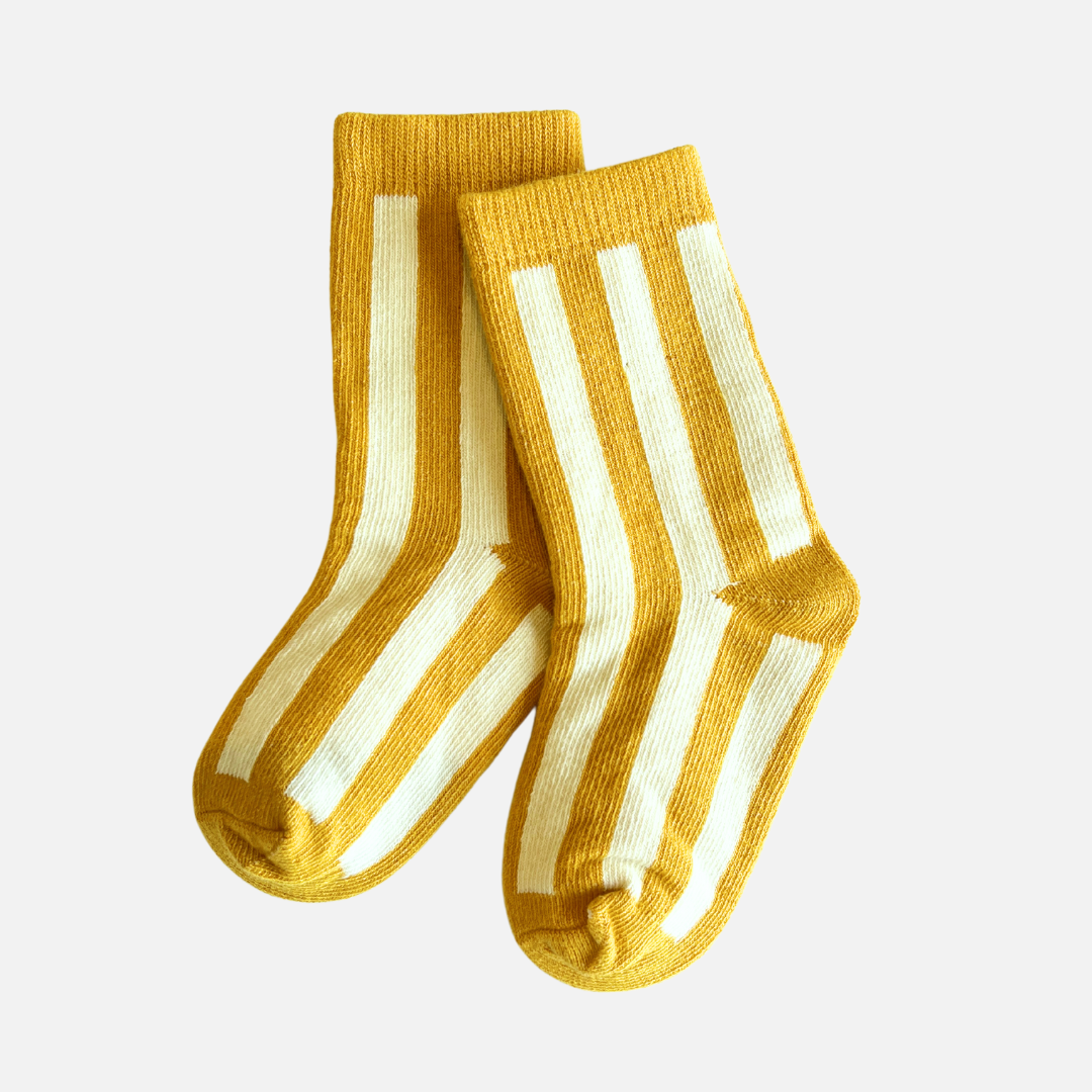 Pair of yellow socks with white stripes on a light gray background