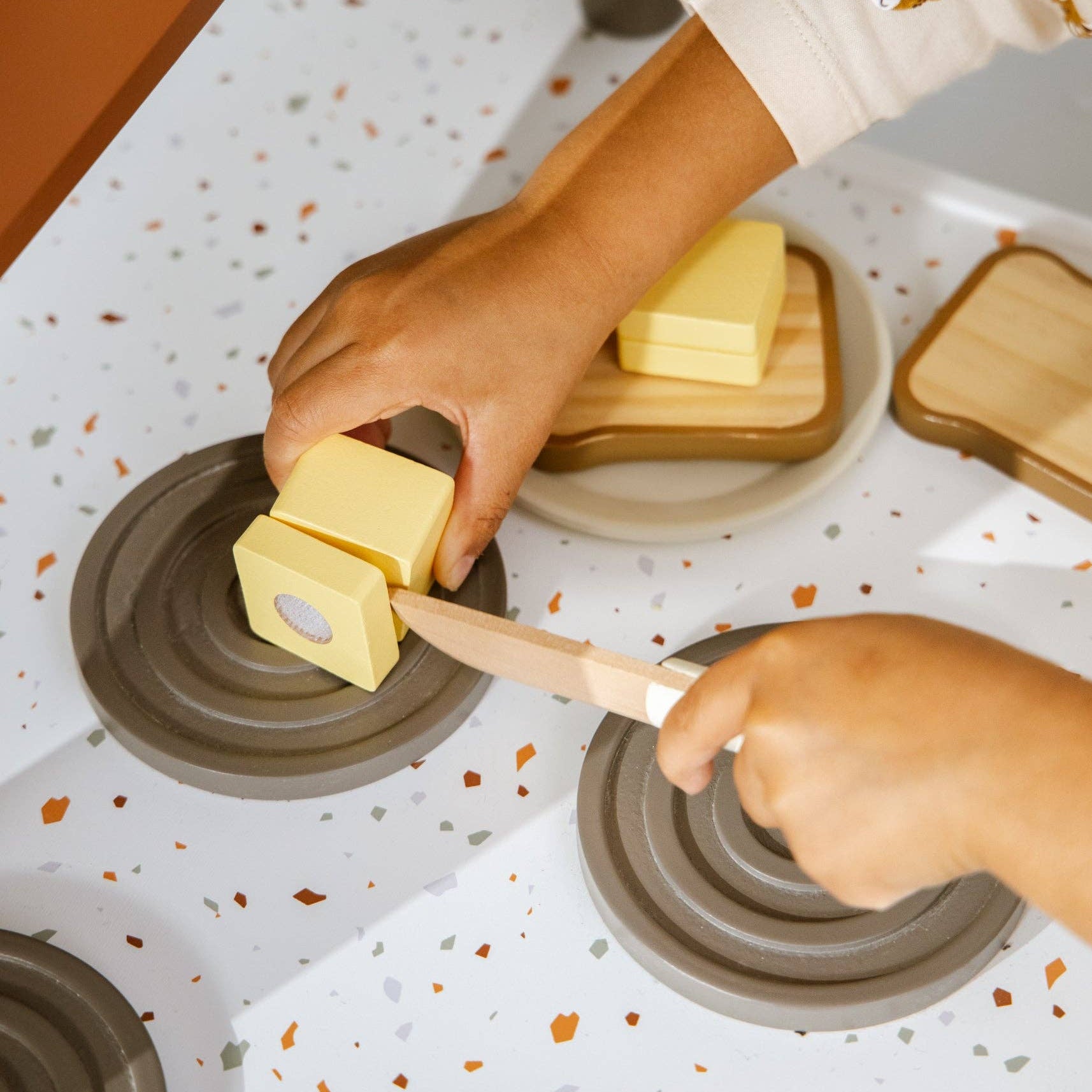Person using a knife to cut butter on a speckled countertop