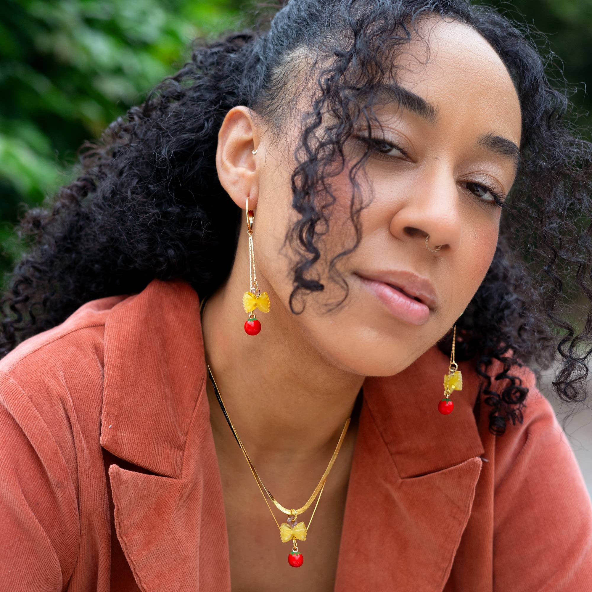 Woman wearing a rust-colored jacket with a blurred green background