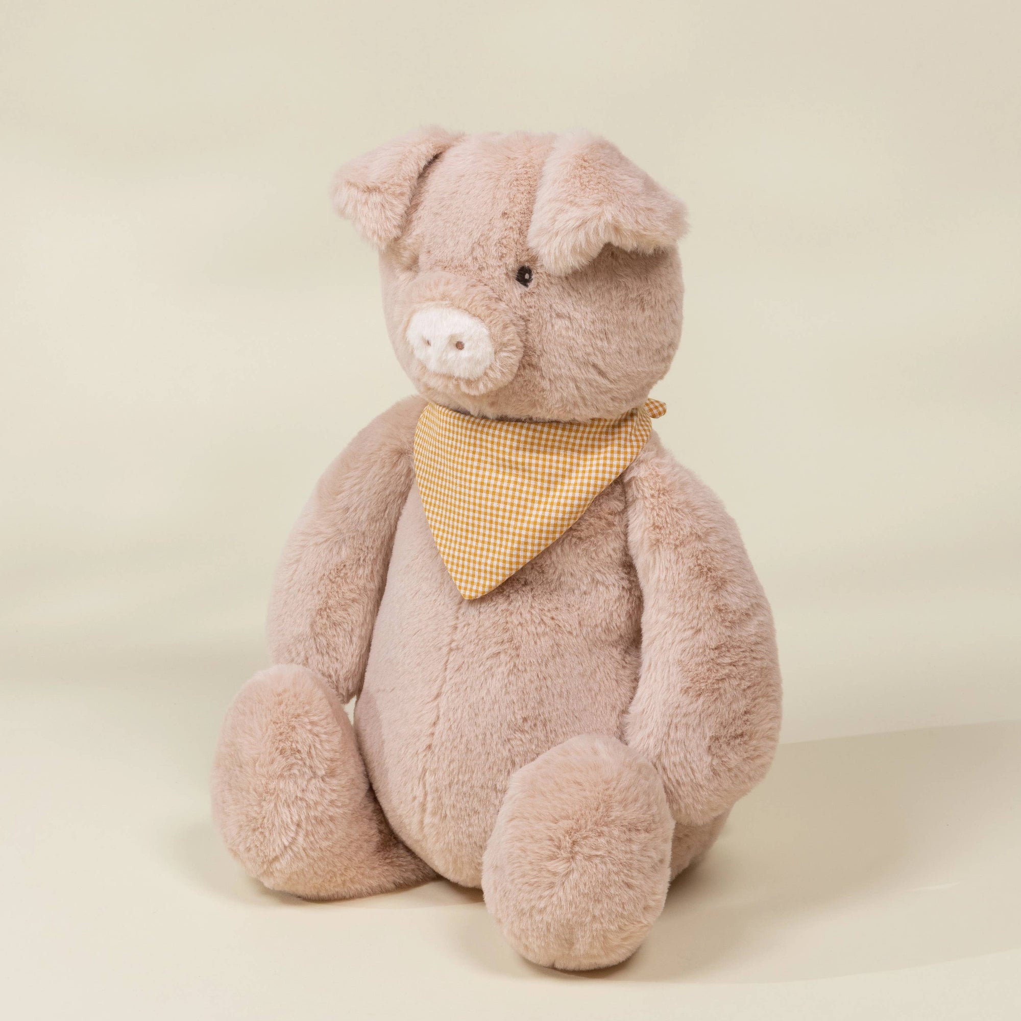 Plush teddy bear with a yellow bandana on a beige background