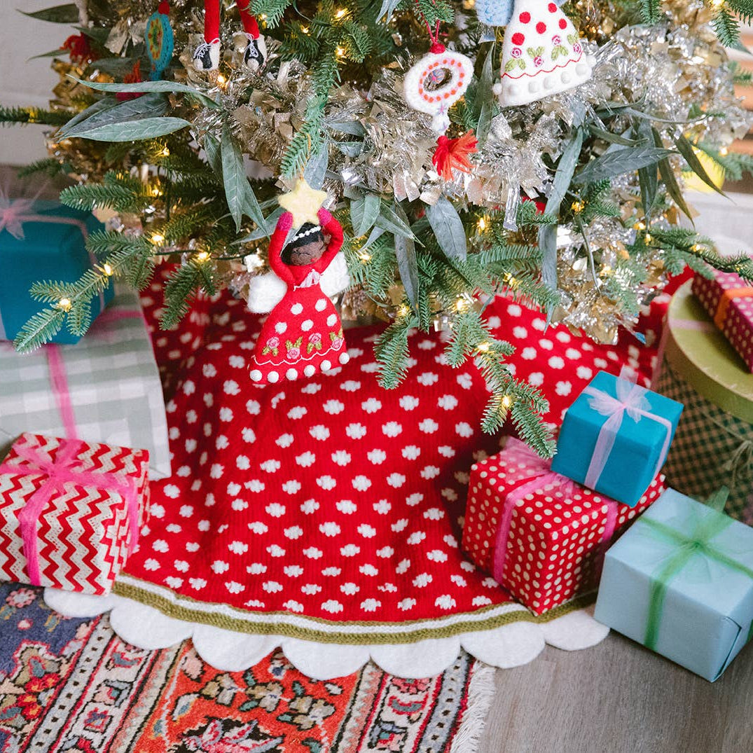 Decorated Christmas tree with a red polka dot skirt and wrapped gifts on a patterned rug.