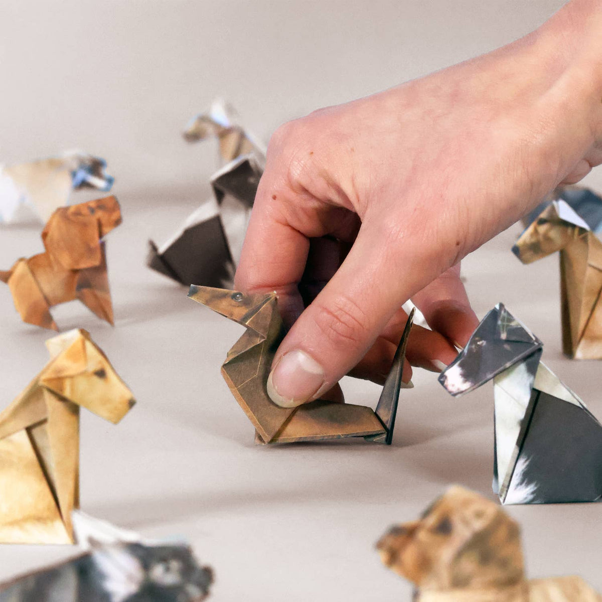 Hand interacting with origami animals on a light surface