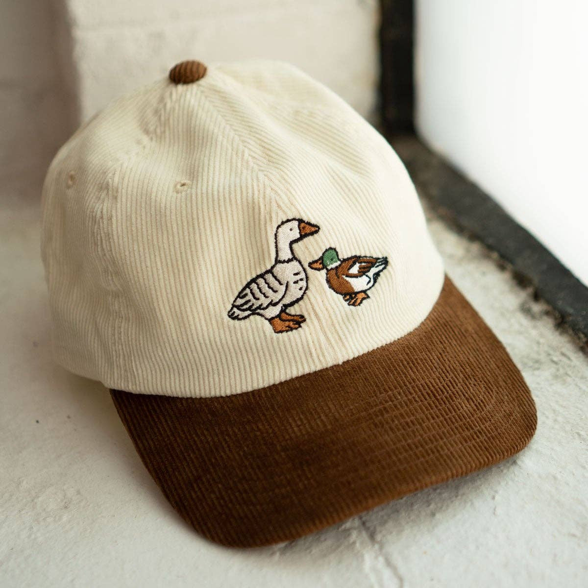 Cap with embroidered goose design on a textured surface