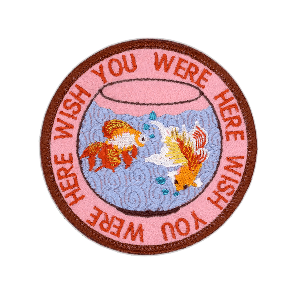 Circular patch with goldfish in a bowl and text 'Wish You Were Here' on a pink background