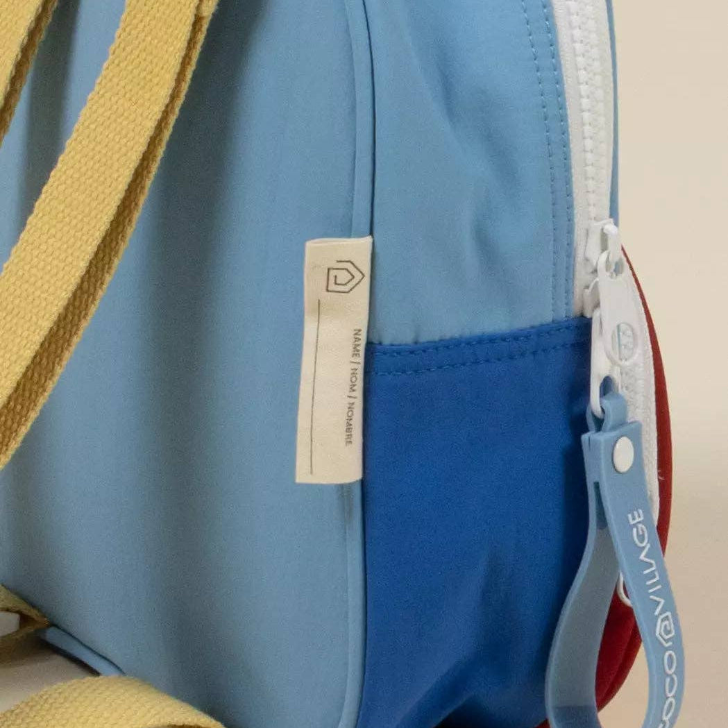 Blue bag with a yellow strap and visible brand tag on a beige background
