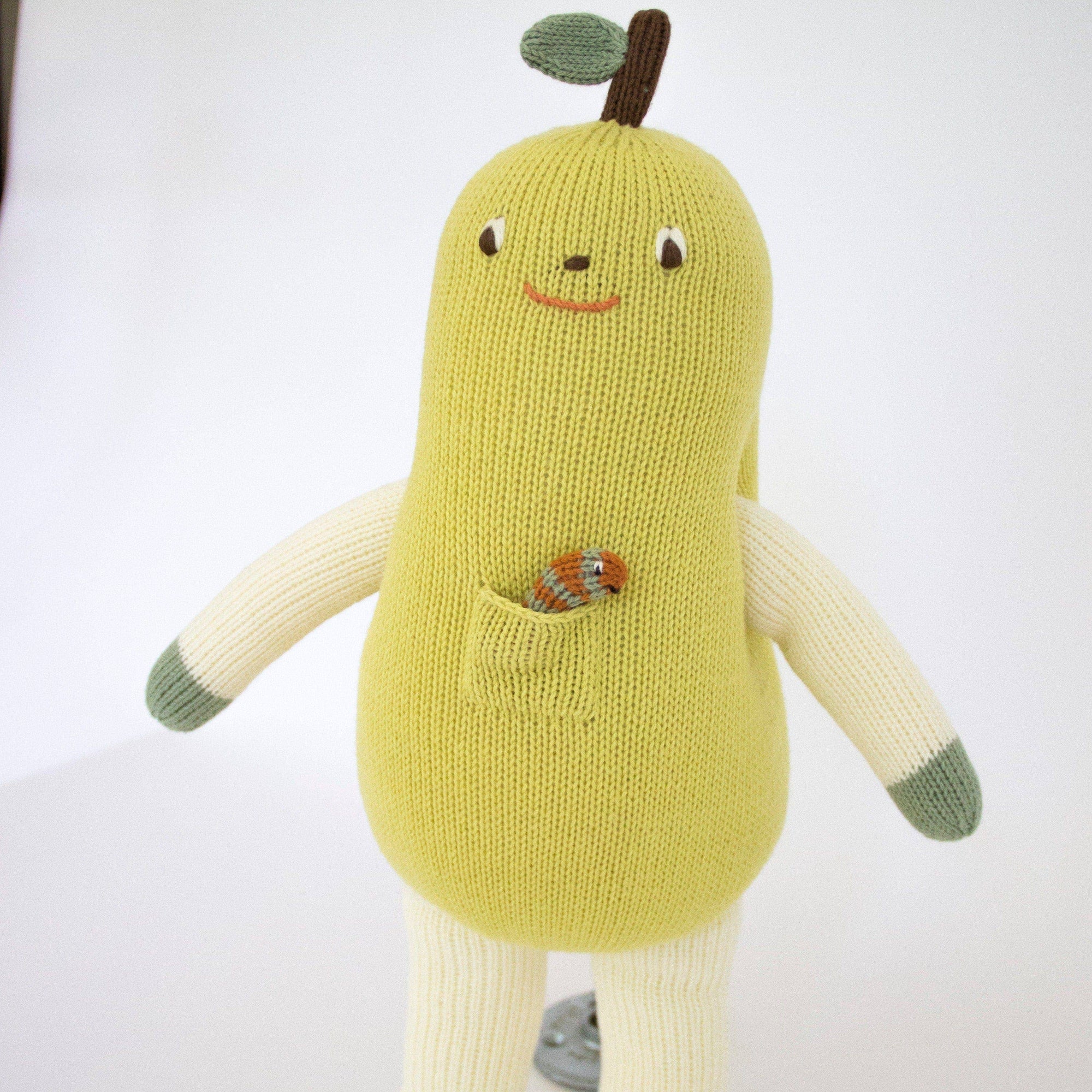 Knitted pear-shaped toy with a face on a white background