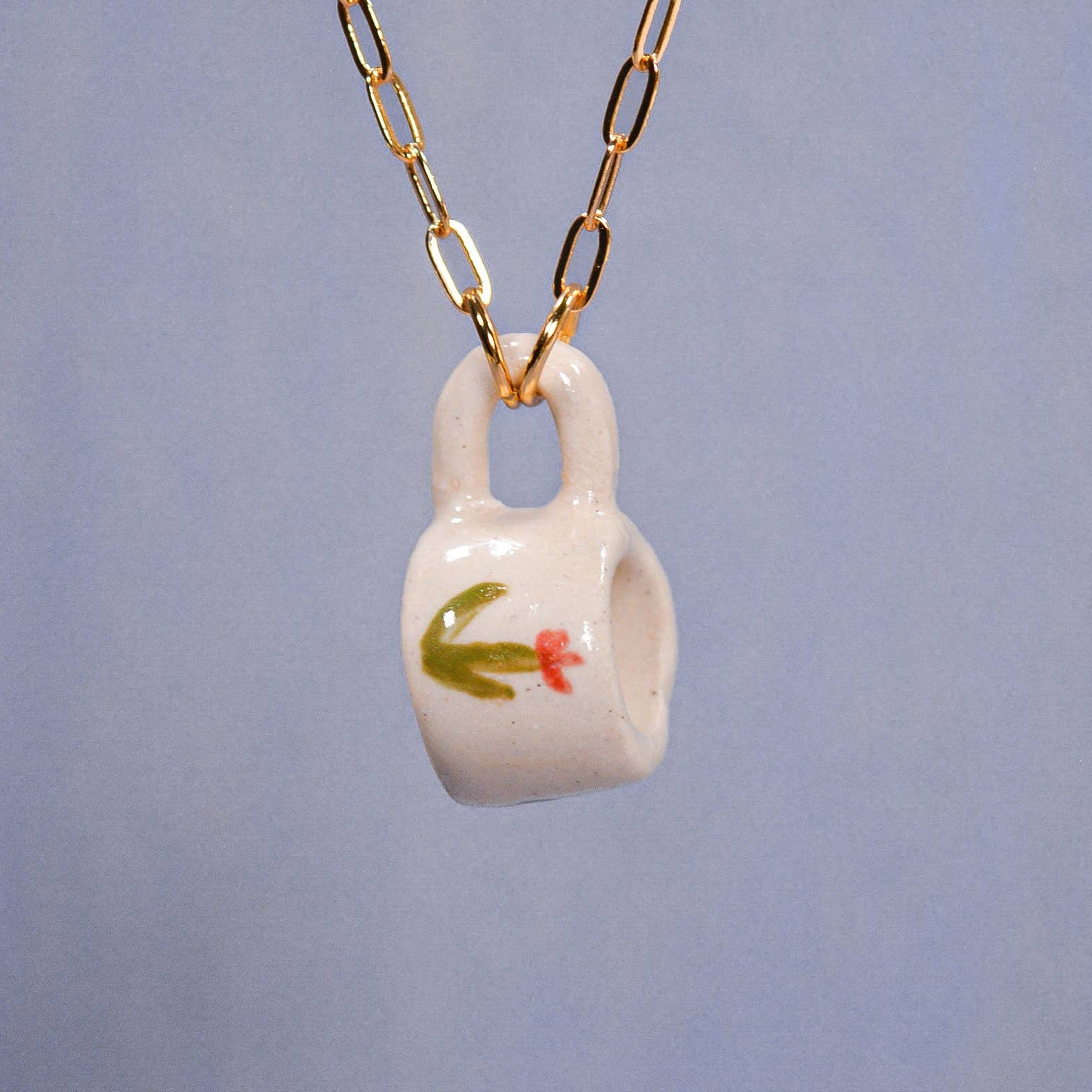 Necklace with a small white ceramic cup pendant on a blue background