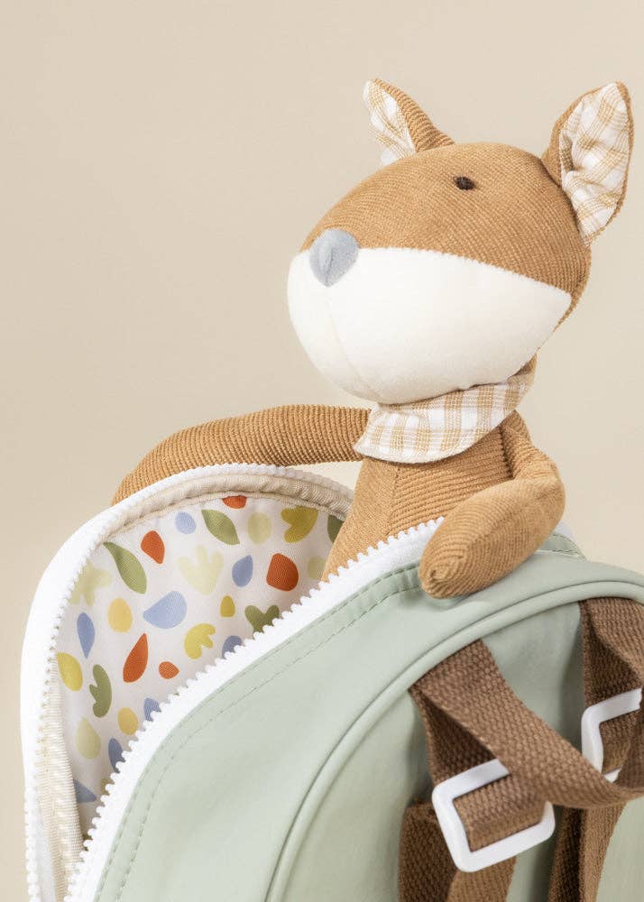Stuffed fox toy with a checkered scarf on a green bag with colorful leaf pattern.